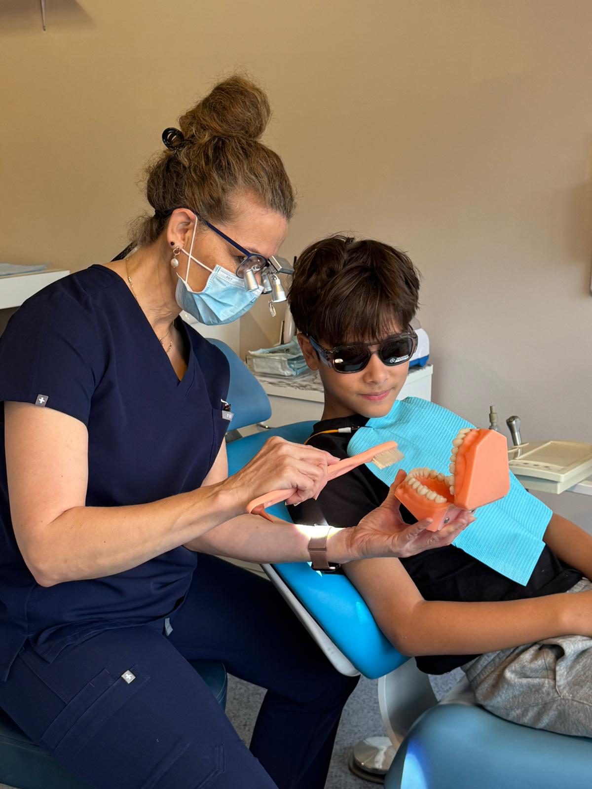Dentist showing a young patient how to brush teeth